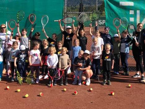Eine Gruppe von Kindern mit Tennisschlägern und Bällen